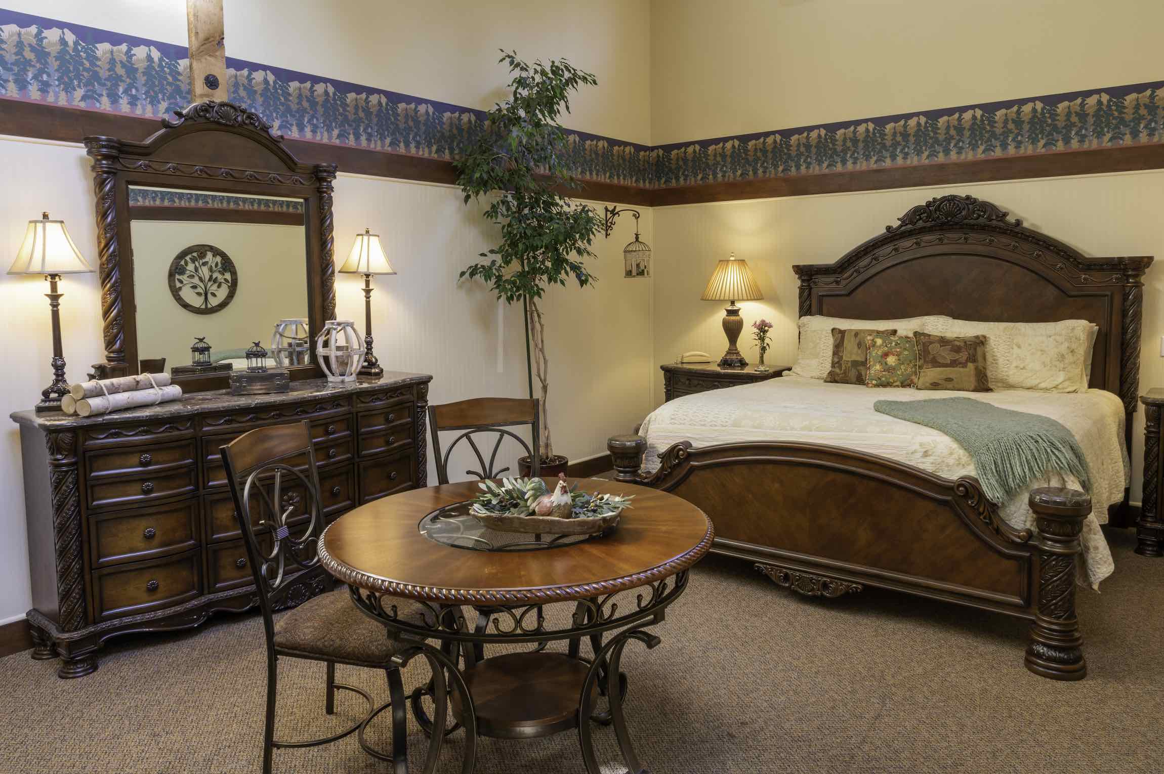 The Creekside Suite bedroom at Country Willows Inn & Estate in Ashland, Oregon has a private deck overlooking the mountains, and a cozy sitting area.