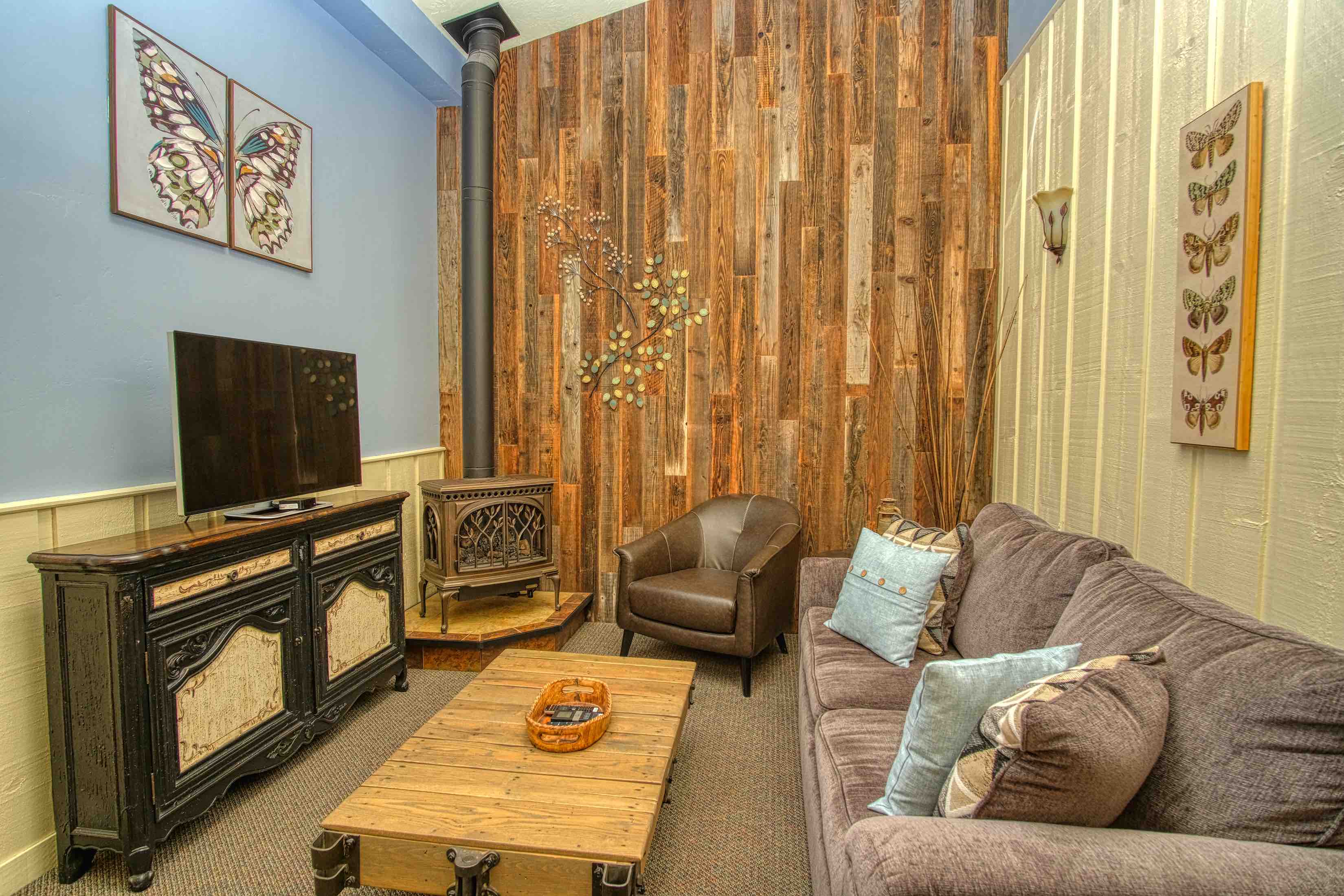 The living room in the Creekside Suite at Country Willows Inn and Estate in Ashland, Oregon has a charming fireplace hearth, antique furniture cart coffee table, and reclaimed redwood accents creating a comfortable, country elegant space.